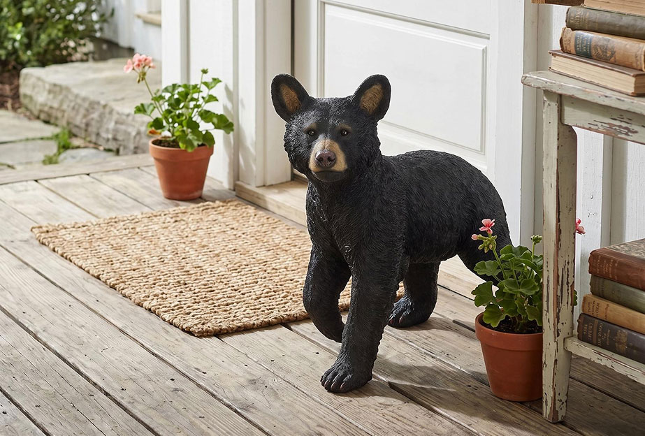 Garden statue - lifelike walking black bear outdoor sculpture in a natural garden setting